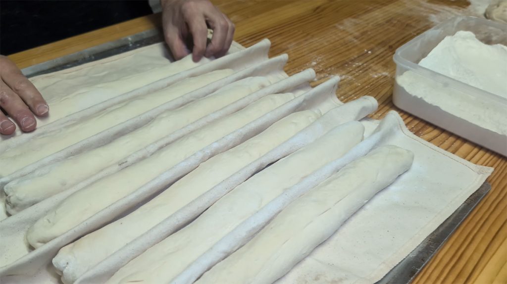 Beginner-Friendly Sourdough Baguettes (Step-by-Step Recipe) 8 Sourdough baguettes separated by a couche, ready for final proof